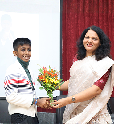 Student Jainam being felicitated with flowers by a school official