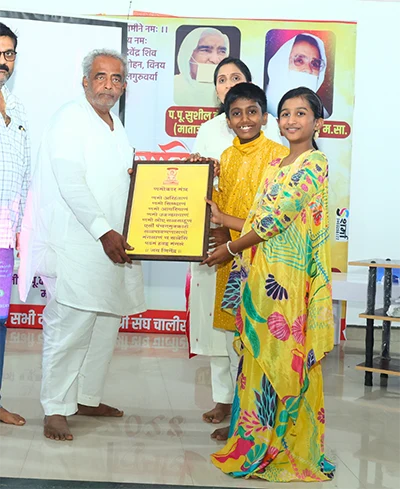 Jainam and Jivika receiving recognition at an event